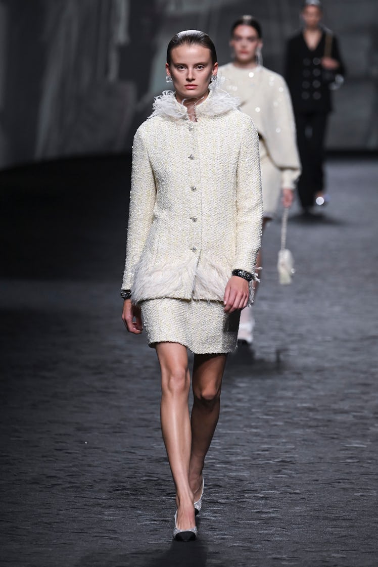 A model wearing Chanel iconic skirt-blazer silhouette in white with feather details at Paris Fashion...