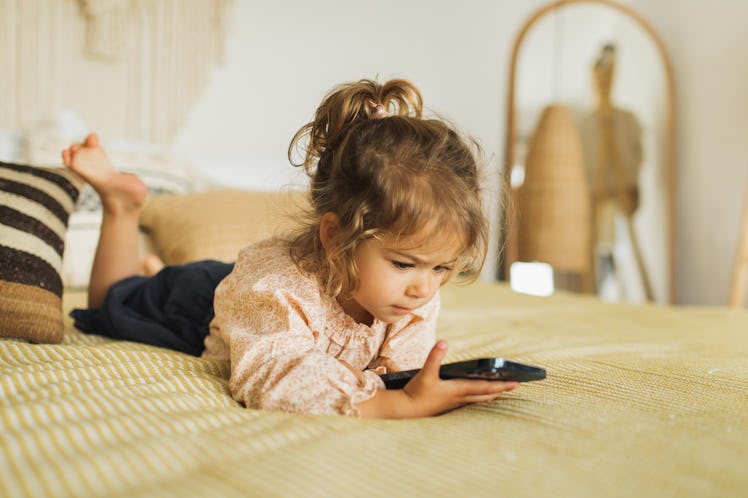 Child watching cartoons on mobile phone. Leisure at home. Digital native. Child using smartphone.