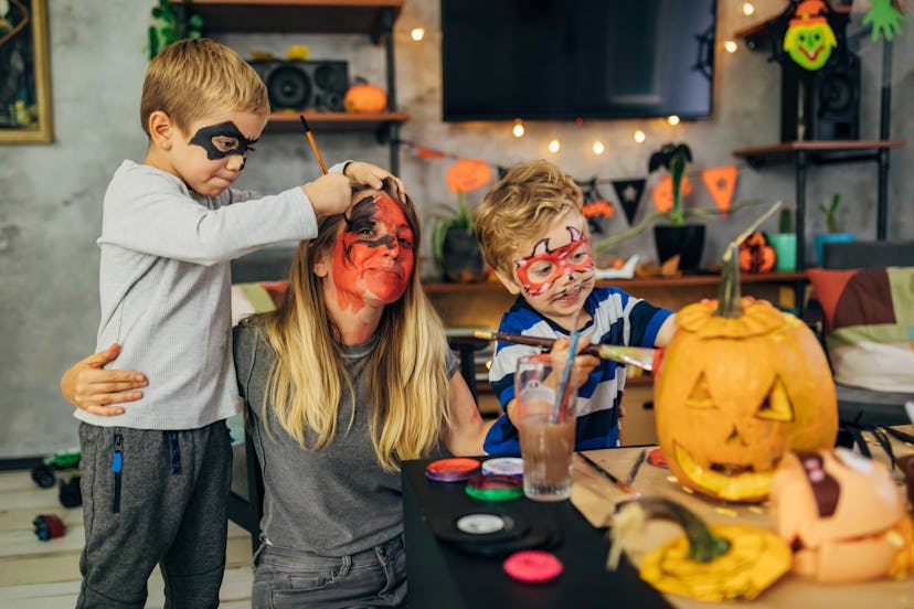 Creative mother with her playful sons, having a fun time, while making the Halloween decoration, enj...