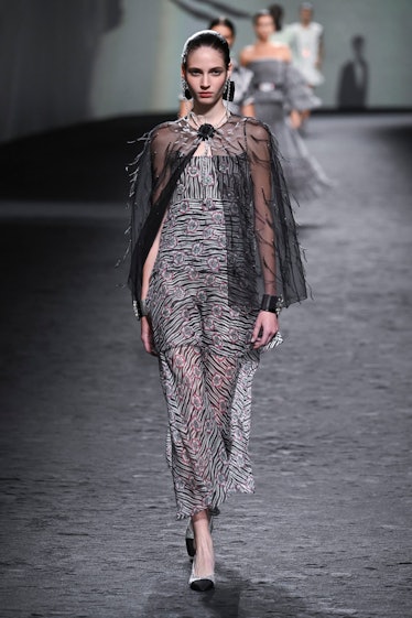 A model wearing Chanel maxi zebra dress and black transparent cape with feather details at Paris Fas...