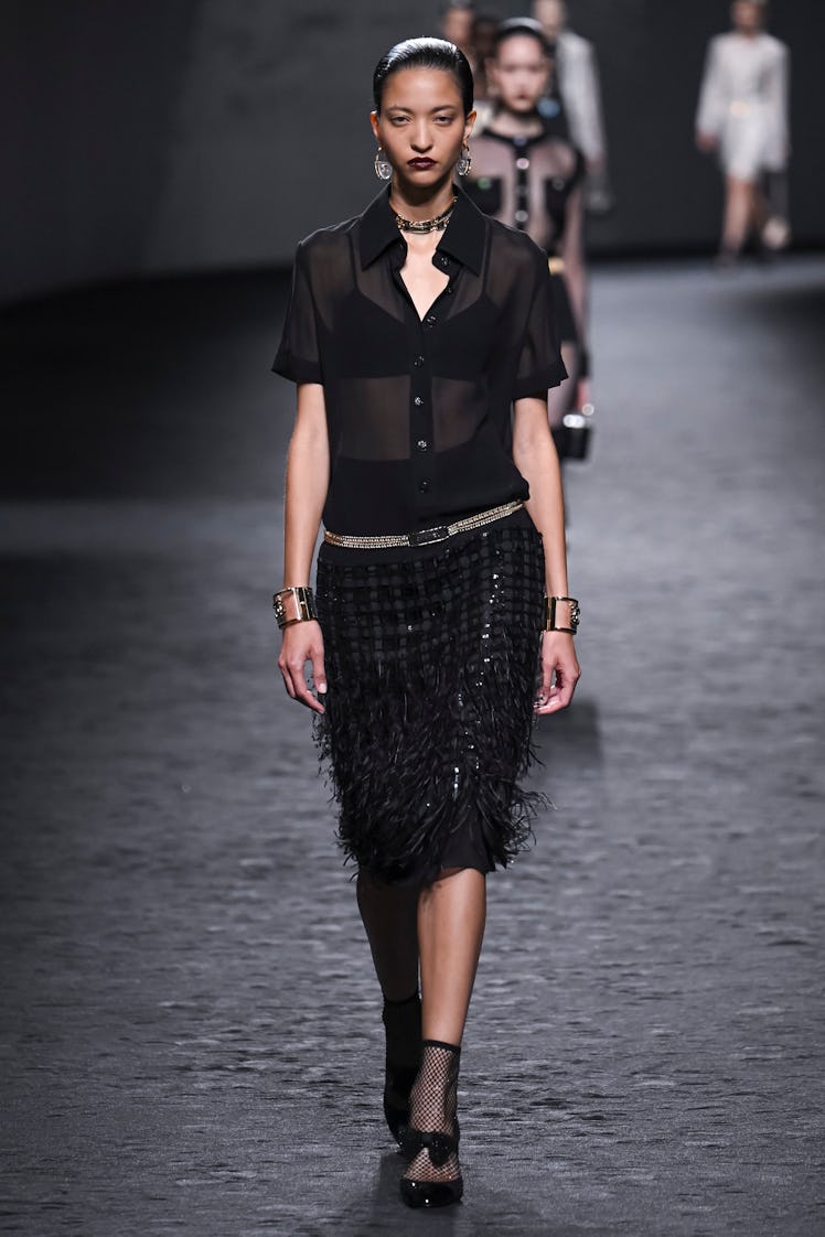 A model in Chanel’s transparent black t-shirt and feather-sequined skirt at Paris Fashion Week Sprin...