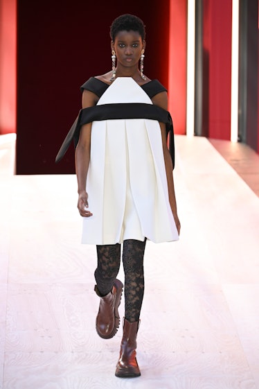 A model wearing a black-white Louis Vuitton dress, lace leggings and burgundy boots at Paris Fashion...