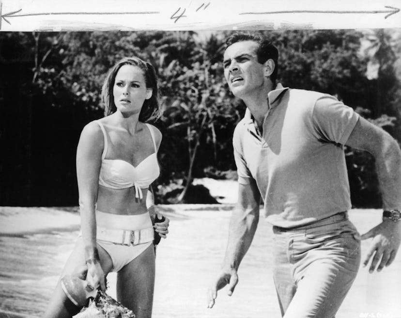 Sean Connery distracted at something he see's while standing near the water at a beach with Ursula A...