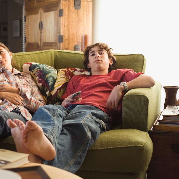 Girl in a striped shirt and jeans with sitting on a sofa with a boy in a red shirt, and jeans who is...
