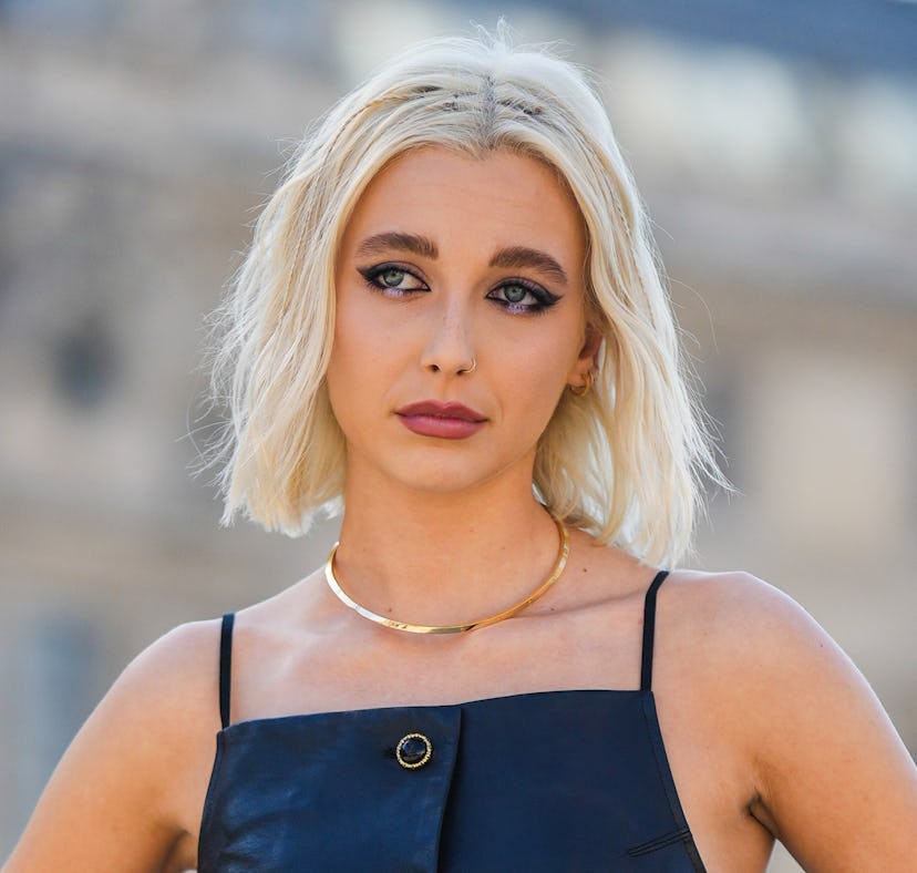 PARIS, FRANCE - OCTOBER 04: Emma Chamberlain wears a black shiny leather square-neck / buttoned long...