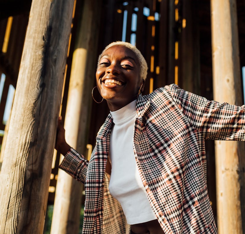 young woman smiles in a plaid blazer as she reflects on her october 17, 2022 weekly horoscope