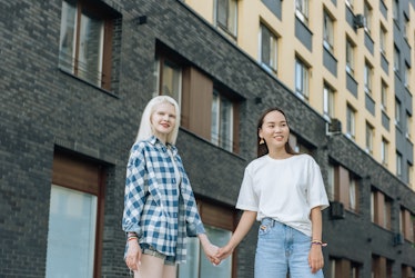 two young women hold hands in the street as they discuss their october 17, 2022 weekly horoscope