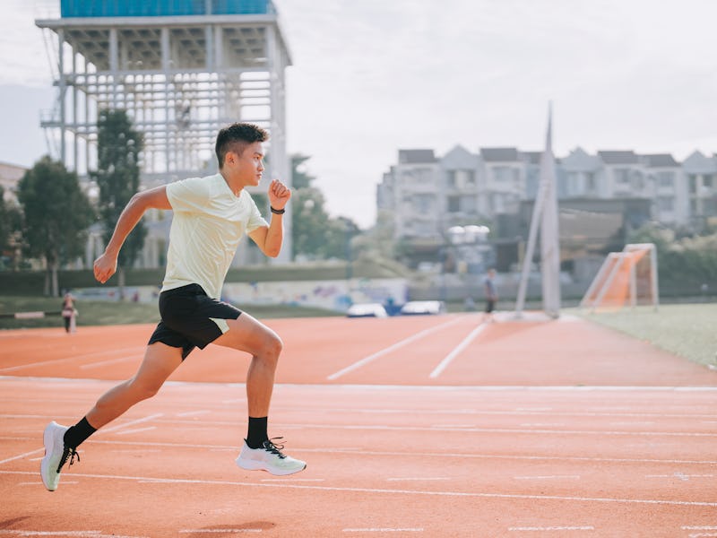Young asian Chinese man athlete training on running track in the morning at track and field stadium