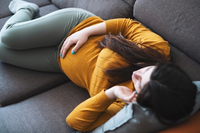 Young pregnant woman at home , laying on sofa , having a headache.