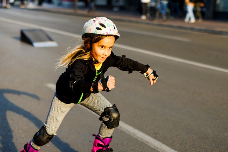 A girl going fast on rollerblades, with helmet and pads on.