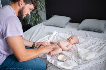Father changing his infant son's diaper.