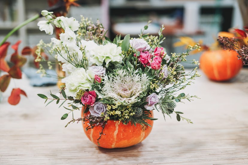 A pumpkin flower arrangement showcasing an array of white, lavender, and pink flowers with greenery ...