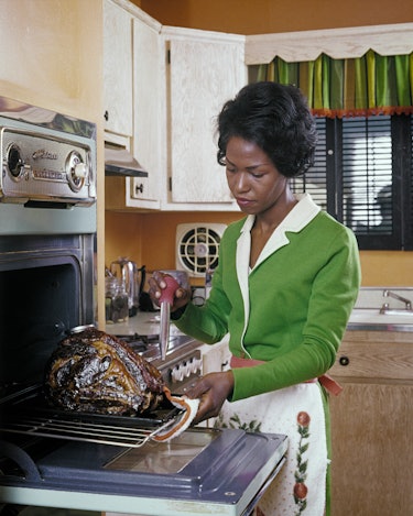 1980s African-American Woman Housewife Basting A Turkey In Electric Wall Oven  (Photo By H. Armstron...