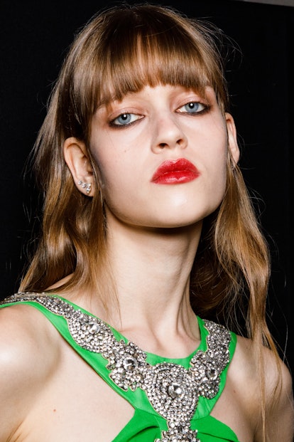A model wearing lip liner and lip stain, the 2022 holiday beauty trend for Virgo, poses in the backs...