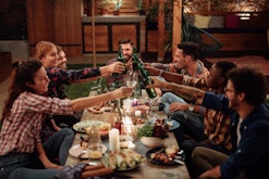 Happy diverse friends toasting at friendsgiving dinner party