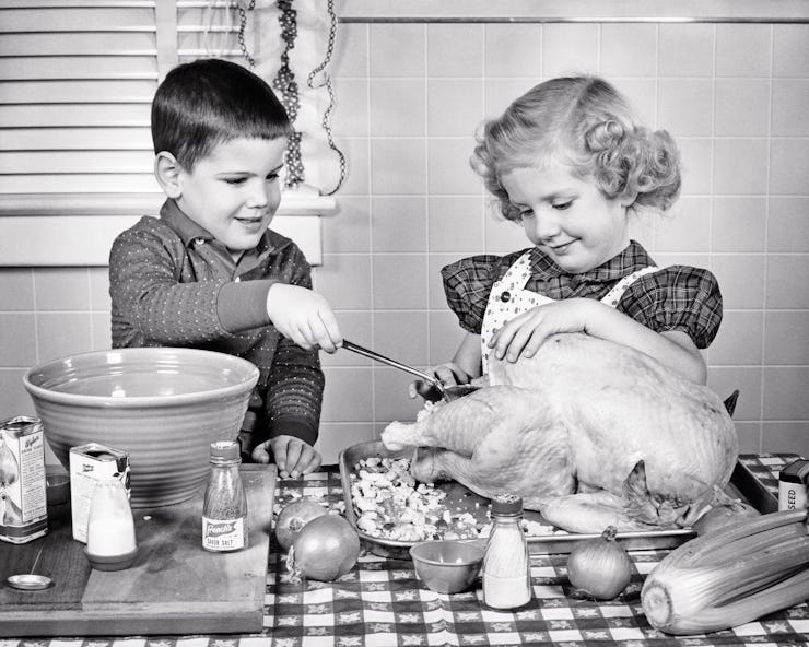 1950s SMILING BOY AND GIRL BROTHER AND OLDER SISTER LADLING BREAD STUFFING INTO THANKSGIVING TURKEY ...