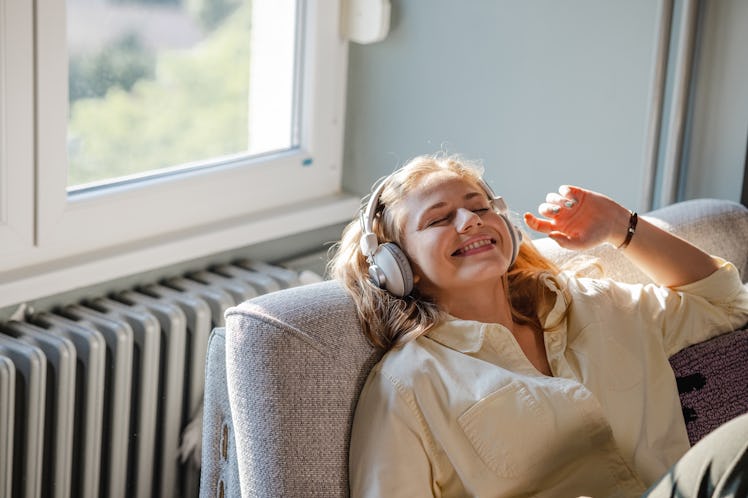 young woman relaxes on the couch and listens to music as she thinks about her november 21, 2022 week...