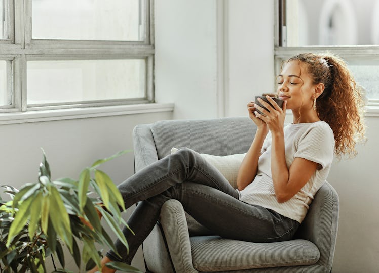 young woman sips on tea as she considers how she'll be affected by the november 2022 new moon