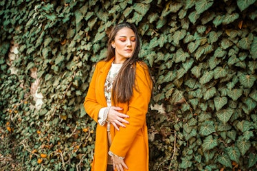 young woman posing in an orange coat as she thinks about her november 21, 2022 weekly horoscope 