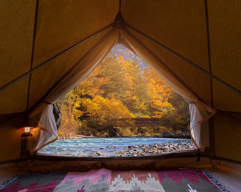 An autumn landscape view from inside of a large tent, demonstrating top fall camping tips.