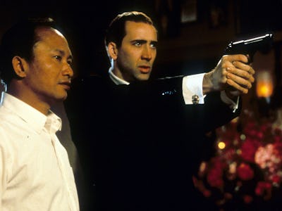 Director John Woo watches as Nicolas Cage aims pistol in between scenes from the film 'Face/Off', 19...