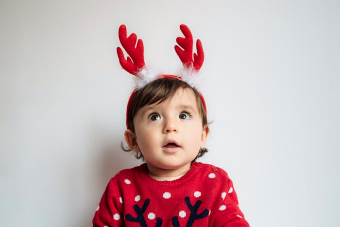 Adorable baby wearing christmas reindeer antlers, superstitions about christmas babies