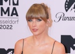 Taylor Swift, wearing a revealing, bejeweled gown with a see-through skirt, poses on the 2022 MTV Eu...