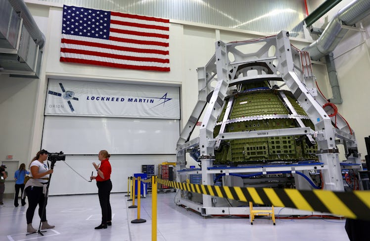 Orion program engineers talk in front of the Artemis III crew capsule being assembled at Kennedy Spa...