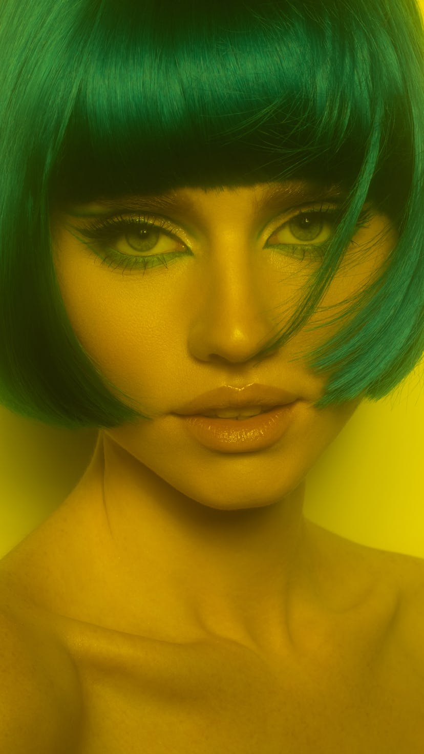 The 2023 haircut trend for Cancer is a chin-length bob as seen on a young woman with green hair.