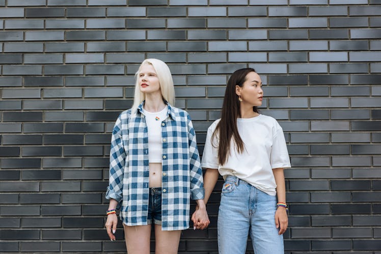 two women hold hands and pose in front of a wall as they discuss their november 28, 2022 weekly horo...