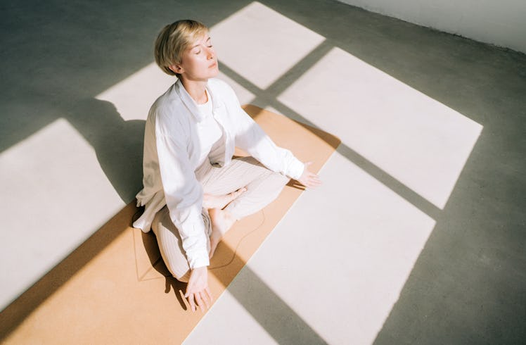 young woman relaxes on a yoga mat as she thinks about her november 28, 2022 weekly horoscope