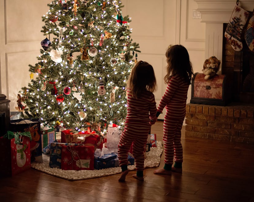  a lit tree with little kids looking at it in an article about is it safe to leave a christmas tree ...
