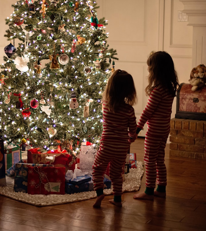  a lit tree with little kids looking at it in an article about is it safe to leave a christmas tree ...