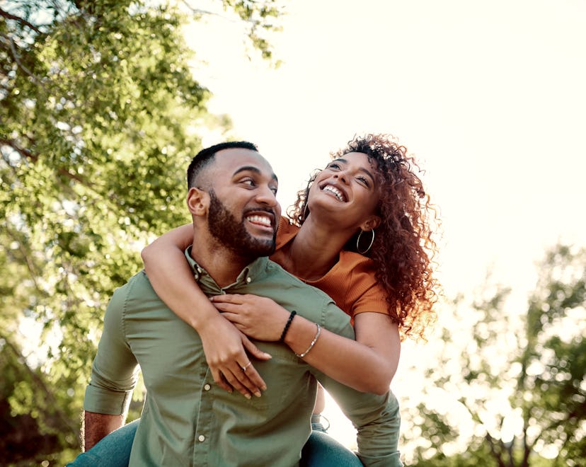 Shot of a young man giving his girlfriend a piggyback ride outdoors