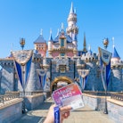 A person holds up their Magic Key to Disneyland, which the Disney Parks are becoming more expensive....