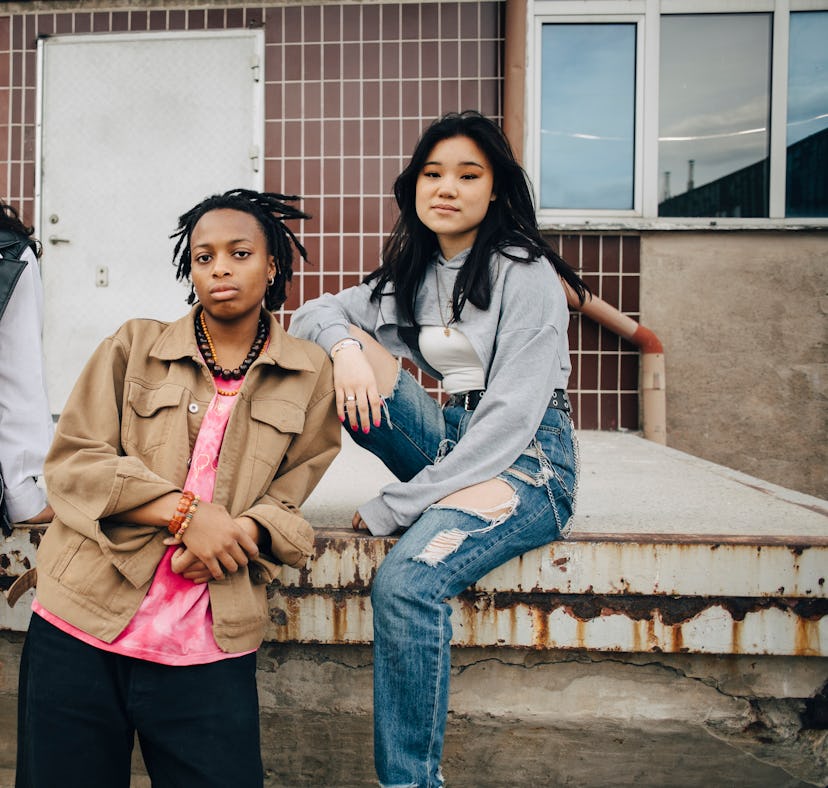 Rhree friends sit outside and gaze into the camera with serious expressions, having the worst month ...