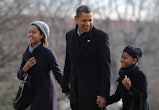 President Barack Obama holds hands with daughters Malia (L) and Sasha upon their return to the White...