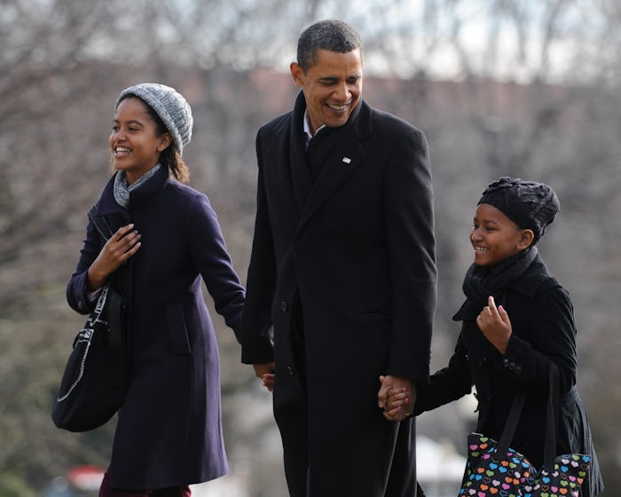 President Barack Obama holds hands with daughters Malia (L) and Sasha upon their return to the White...
