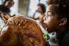 在感恩节大餐上，小黑人女孩在吃烤火鸡的时候玩得很开心。