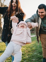 Family with one little daughter at the park together. Caucasian ethnicity. They are having fun toget...