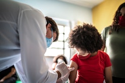 Child getting flu shot with her mother in vaccination center