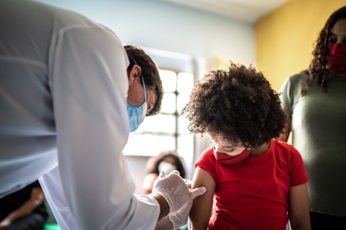 Child getting flu shot with her mother in vaccination center
