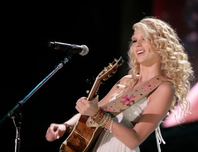 Taylor Swift performs at the Music Festival wearing long blond curls while holding her guitar.