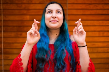 young woman crosses her fingers and looks upward as she considers the spiritual meaning of 11/11