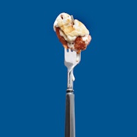 Candied Yam dripping on silver black fork over blue background