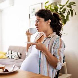 Young pregnant woman alone in her kitchen enjoying a breakfast. A new study suggests that even the s...