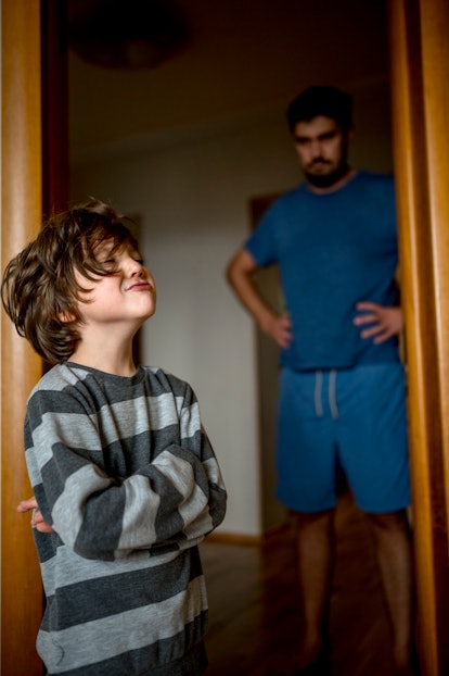 Father with hands on hips lecturing son in article about parenting styles 