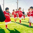 Members of female kids' soccer or football team are warming up before starting training.