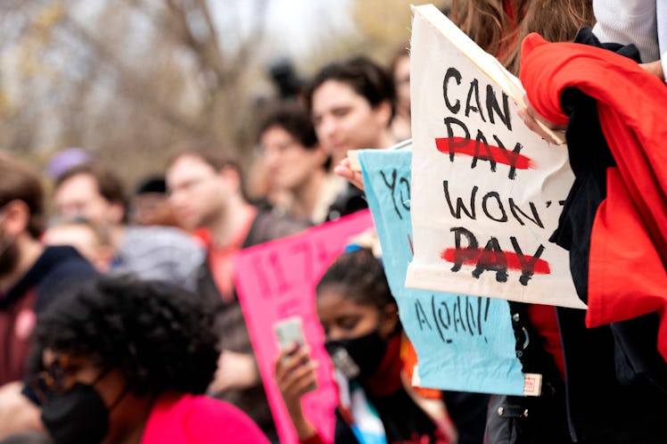 People hold signs during a Cancel Student Debt rally outside the US Department of Education in Washi...