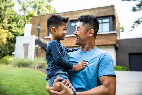 Father holding son in front of modern home